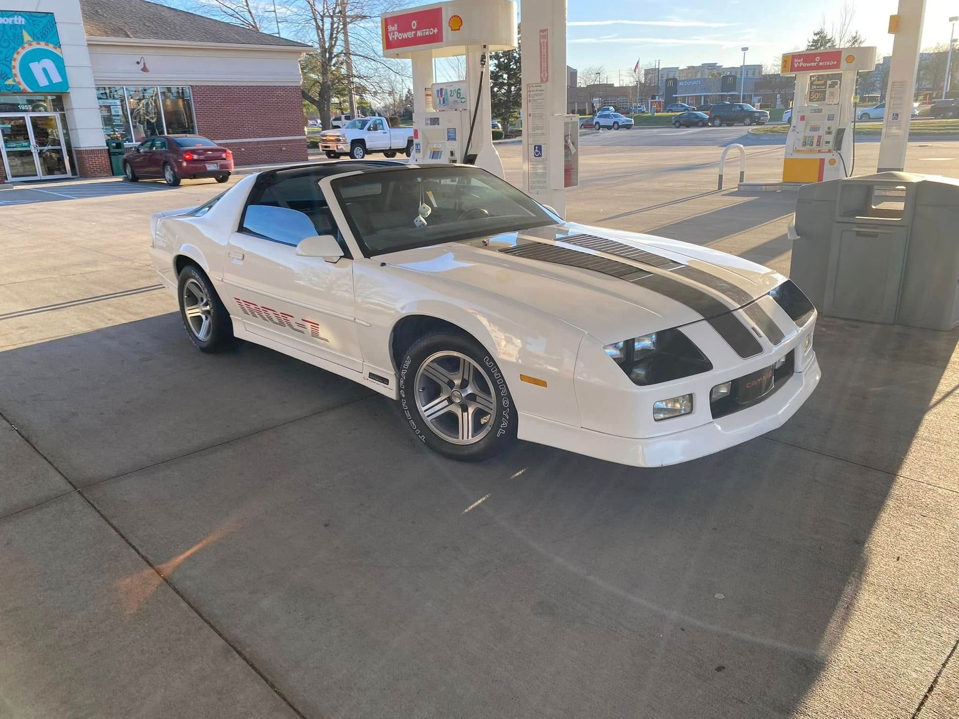 A white car is parked in front of a gas station.