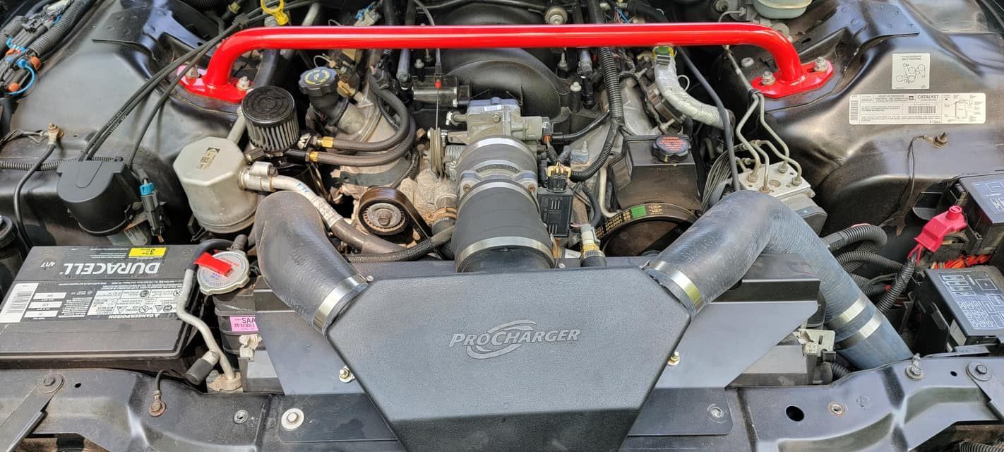A close up of the engine of a car with a red bar.