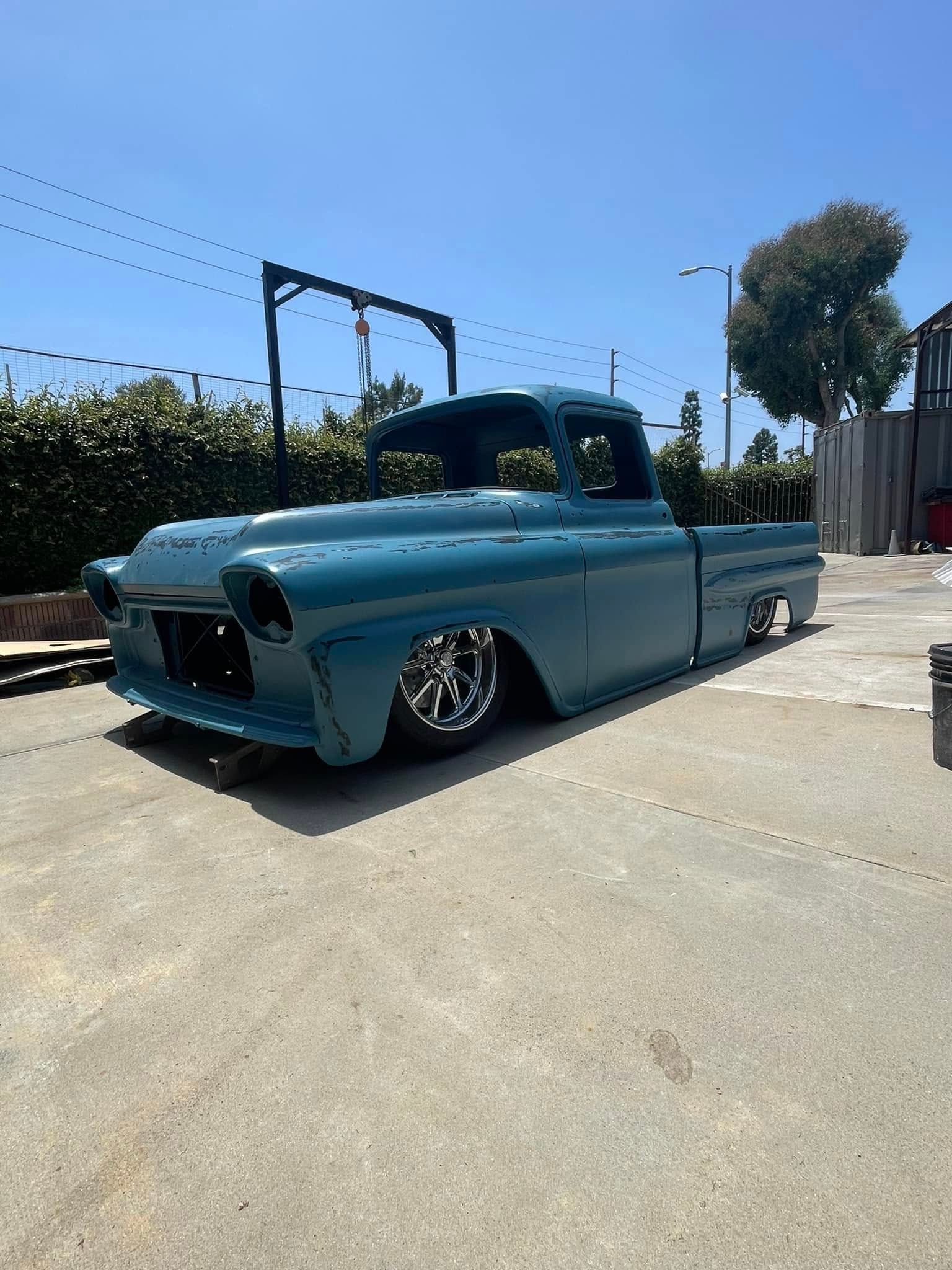 A blue truck is parked in a parking lot on a sunny day.