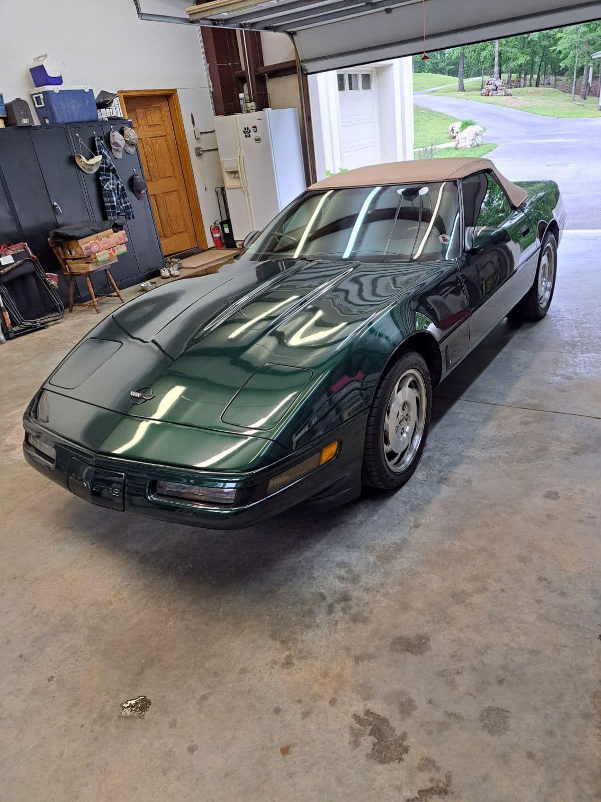A green corvette convertible is parked in a garage.