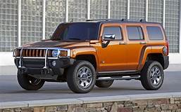 A hummer h3 is parked on the side of the road in front of a building.