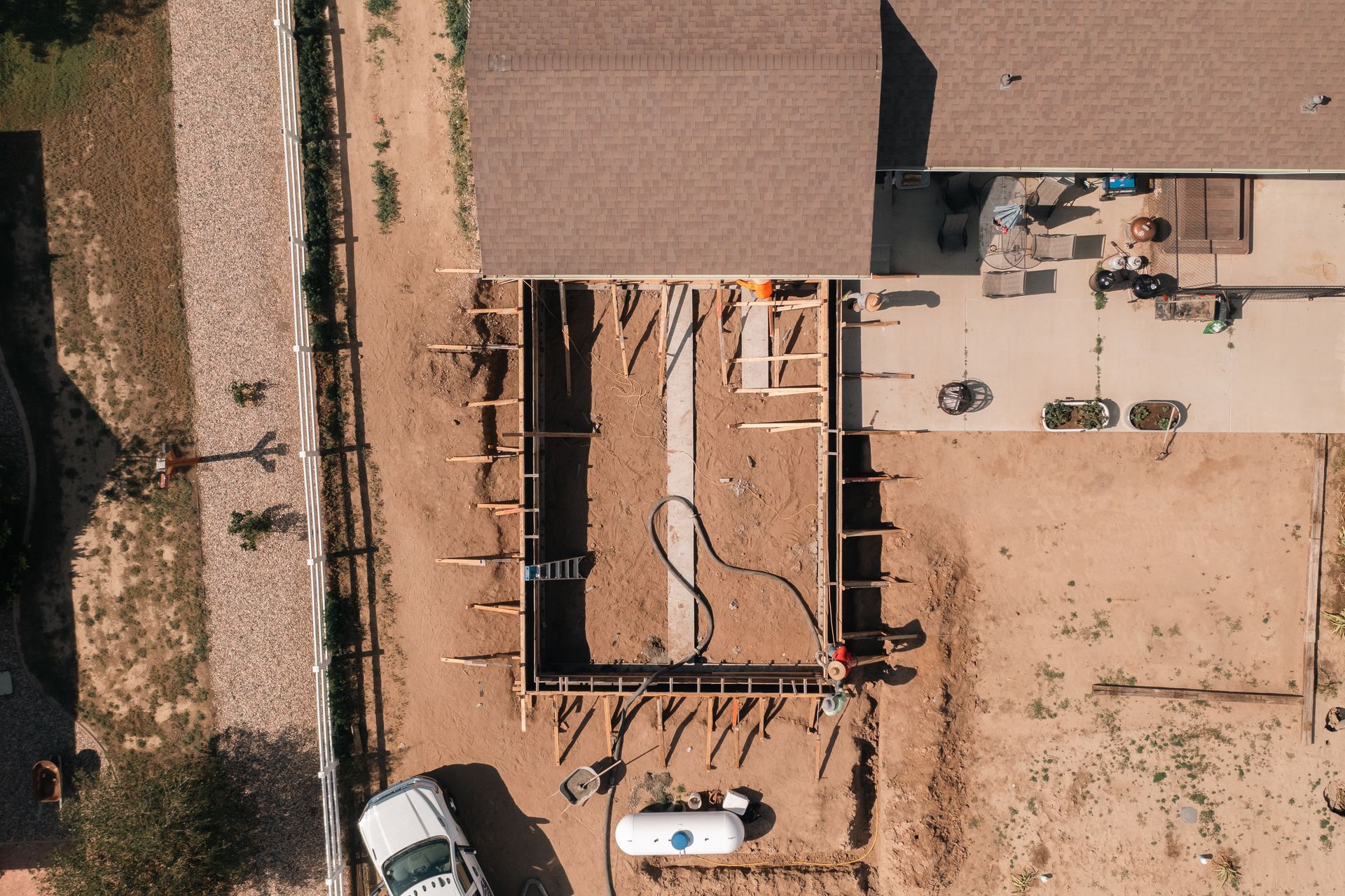 Overhead view of a construction site with a rectangular foundation, framing, and equipment.