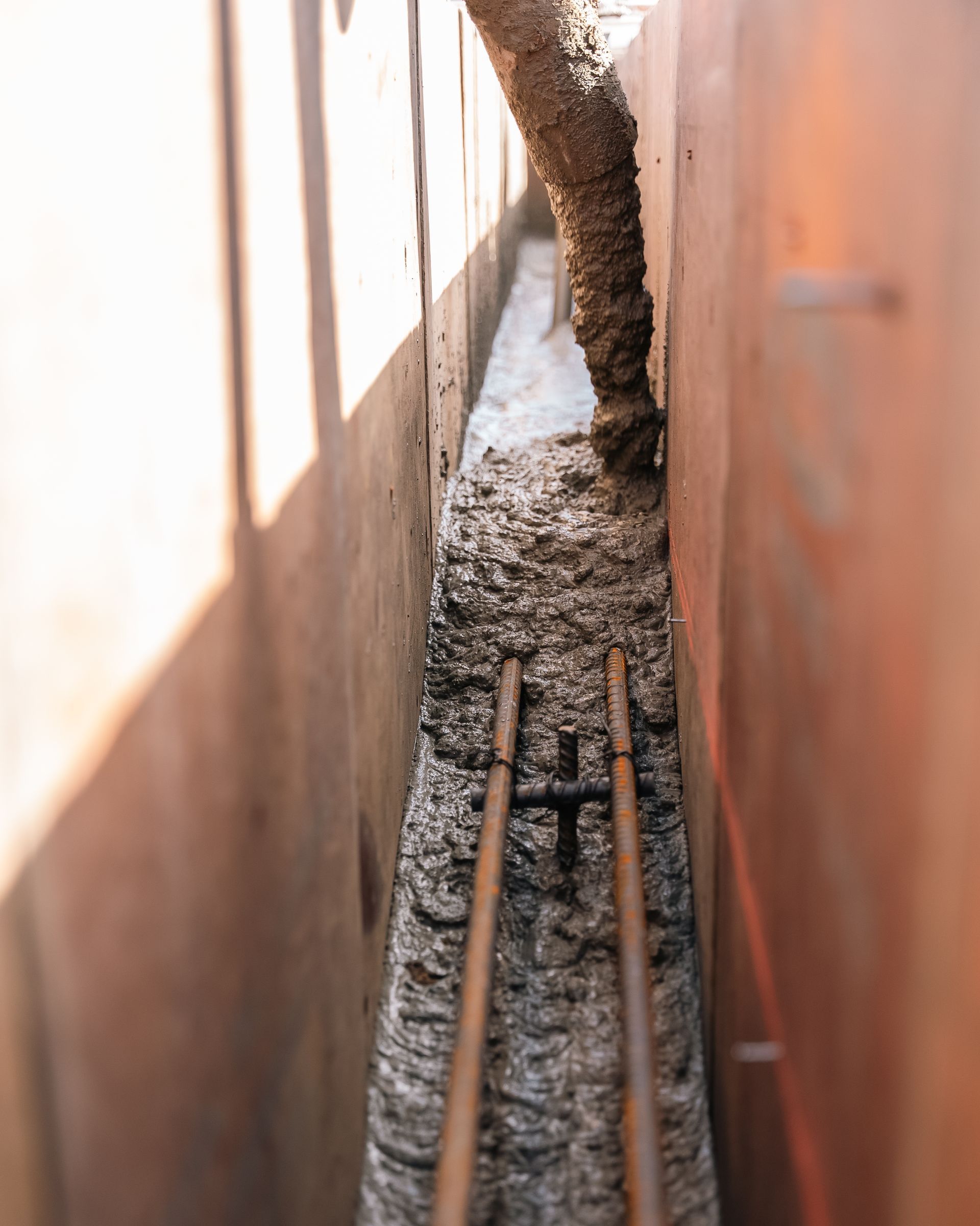 Narrow trench with concrete base; two parallel pipes laid in it.