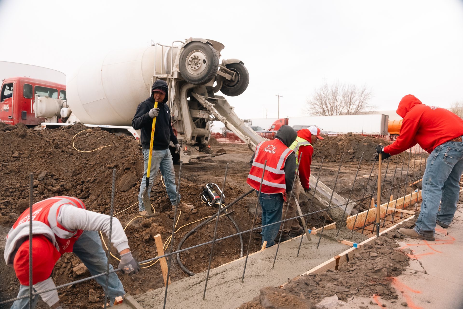 Construction workers pouring concrete from a cement truck into a formwork, outdoors.
