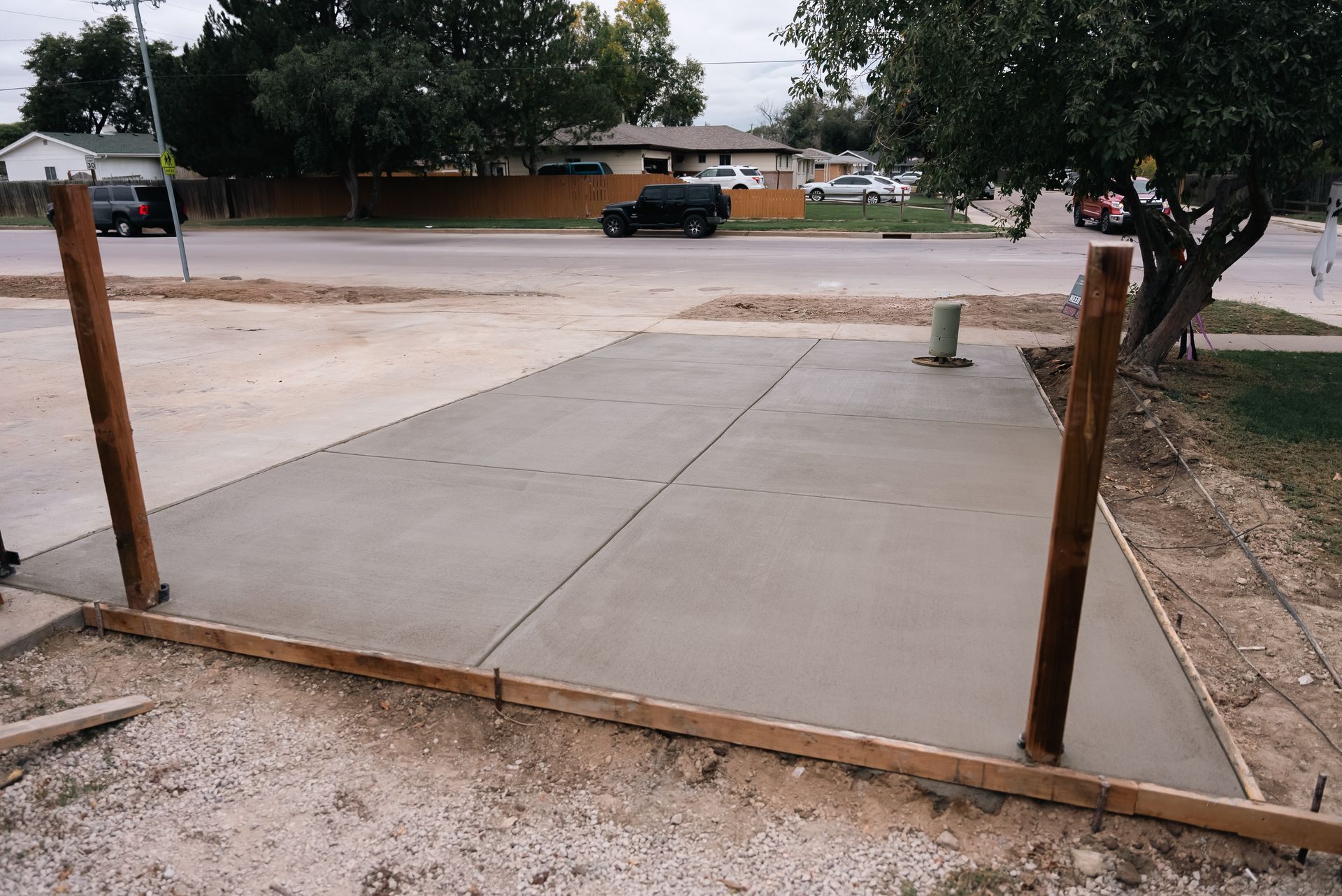 Freshly poured concrete driveway with wooden framing and posts.