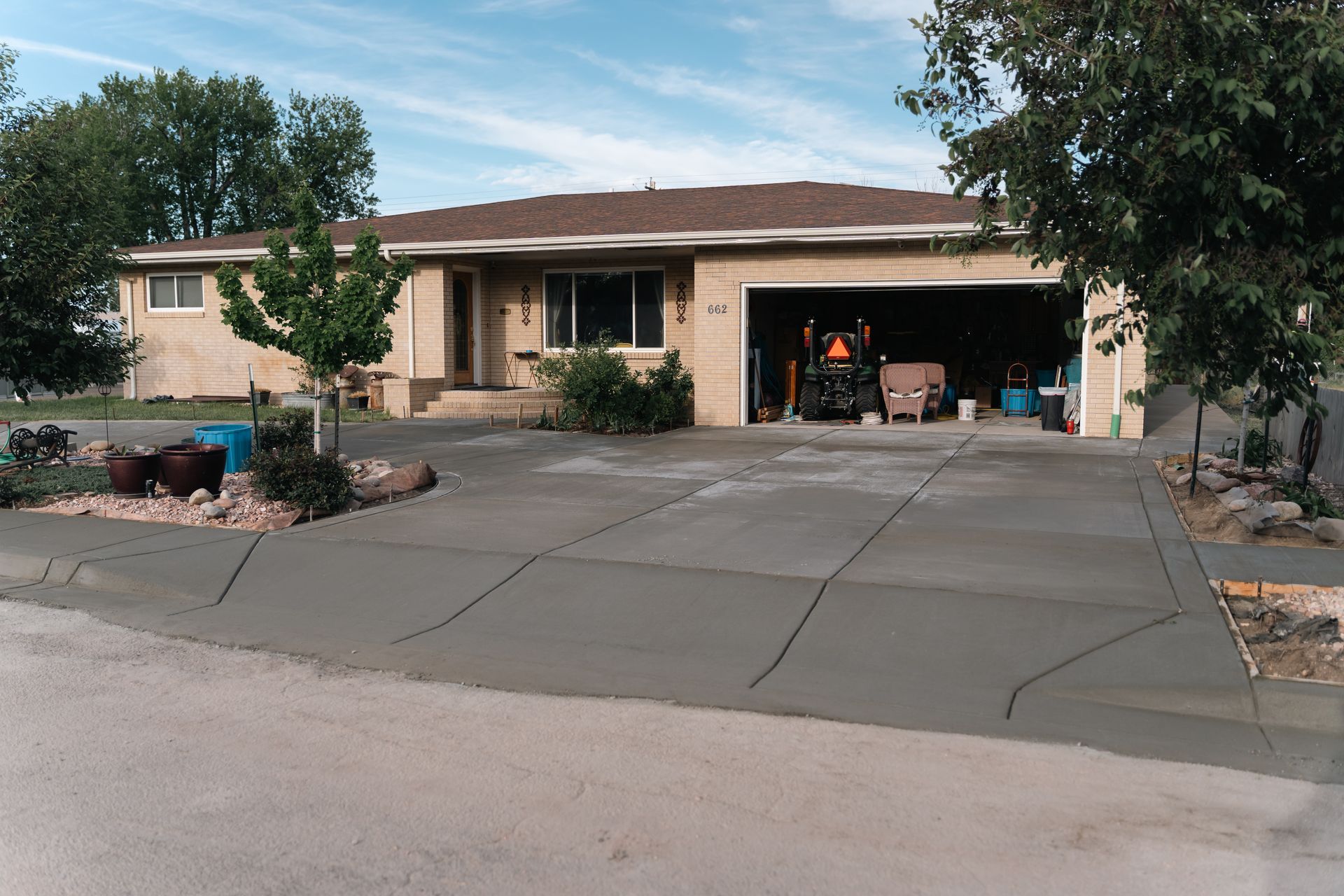Suburban home with new concrete driveway, open garage, and landscaped yard.