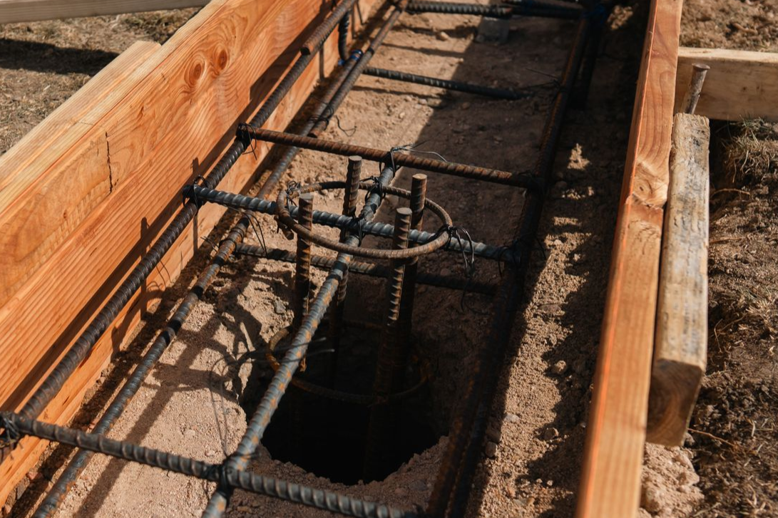 Wooden formwork with steel rebar reinforcement for concrete, set in soil.