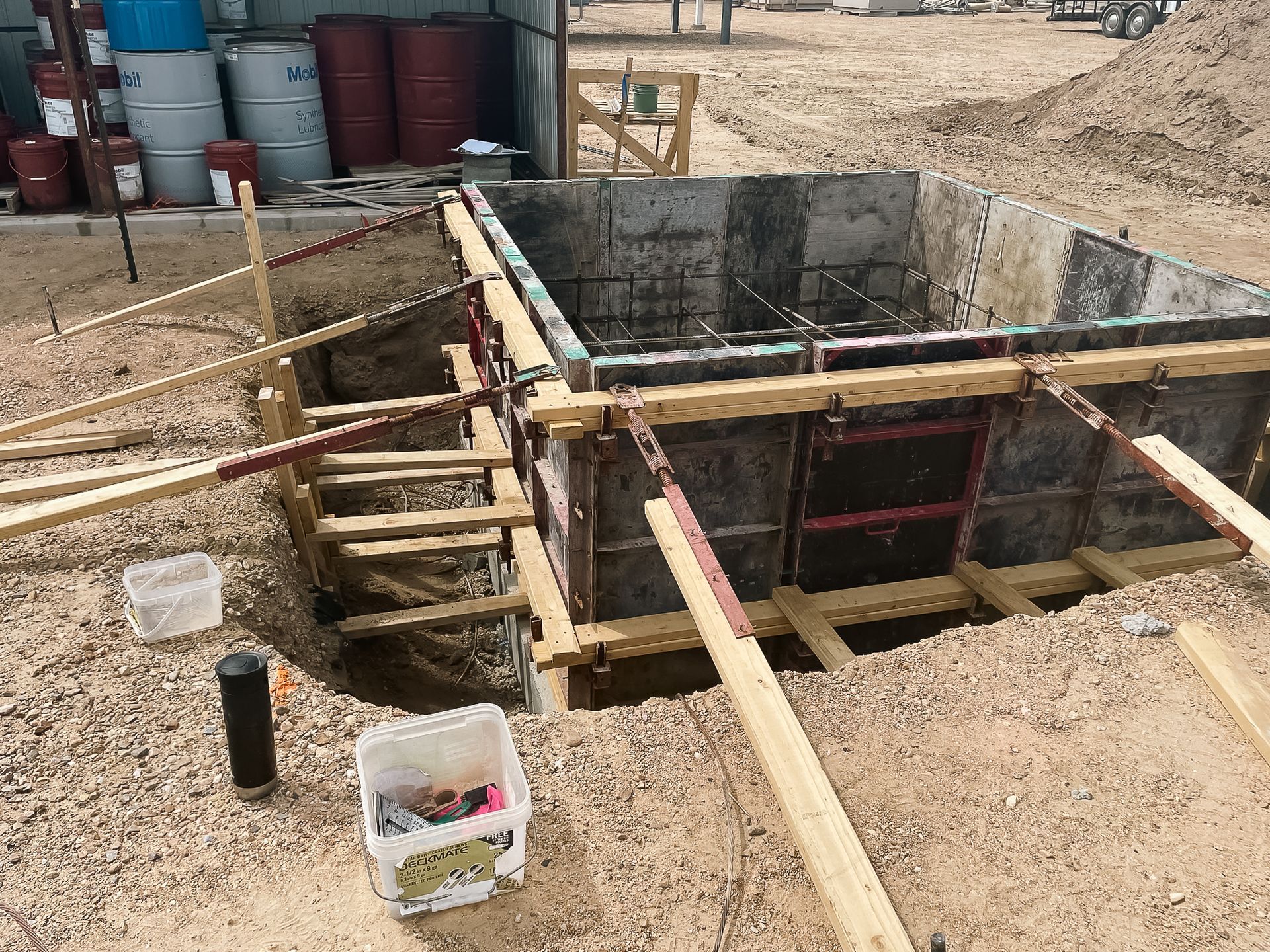 A large concrete tank is being built on a construction site.