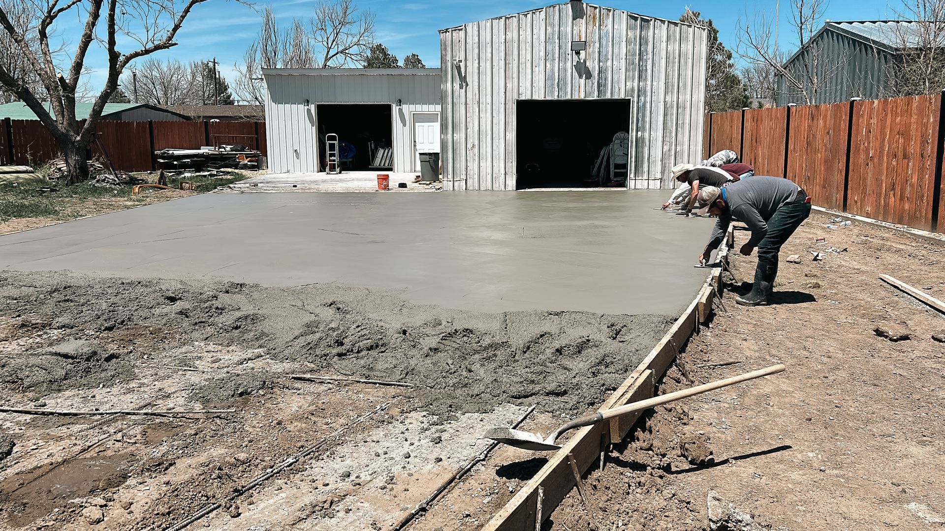 A man is working on a concrete driveway in front of a garage.