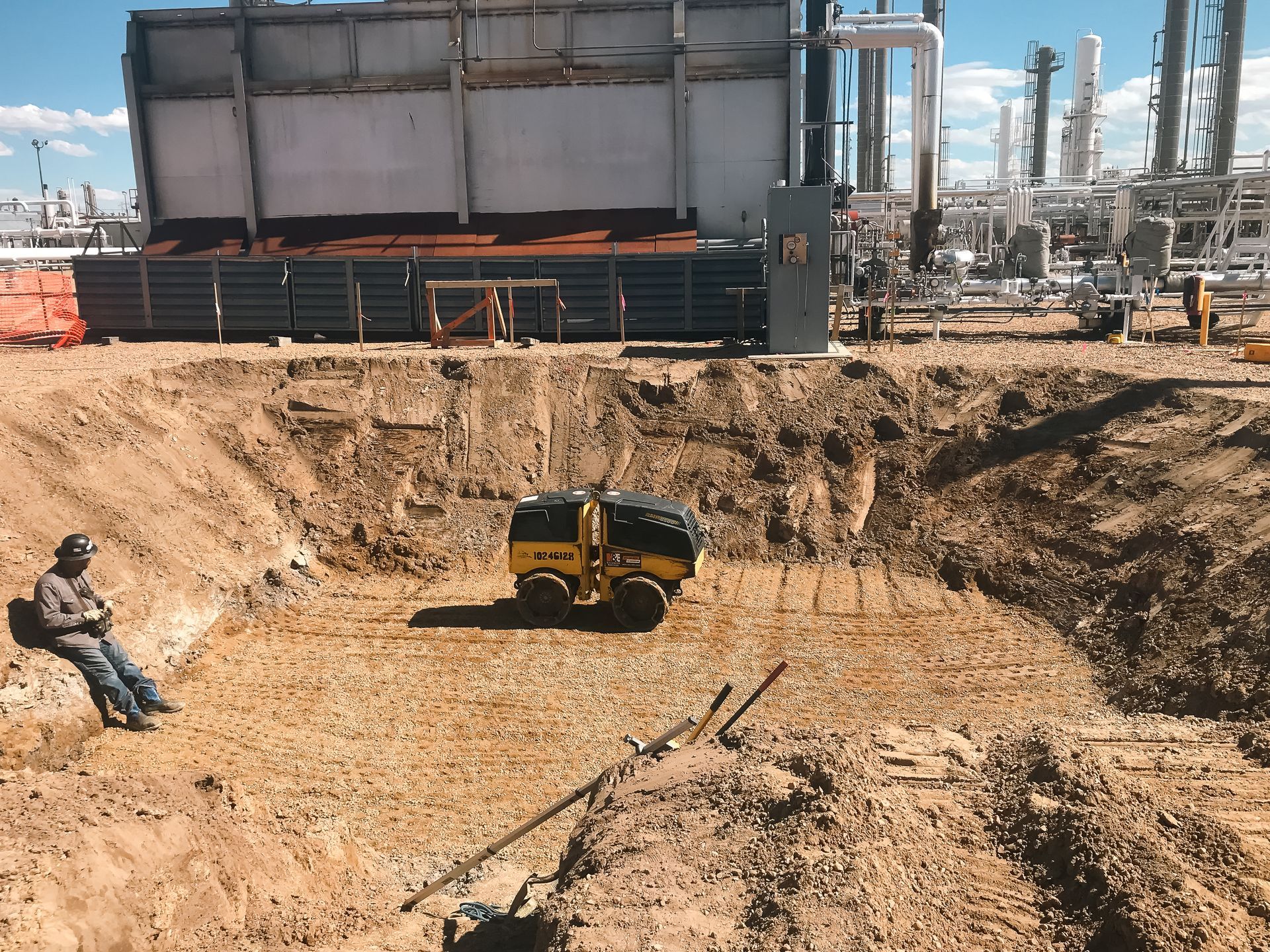 A man sits in the dirt in front of a large building
