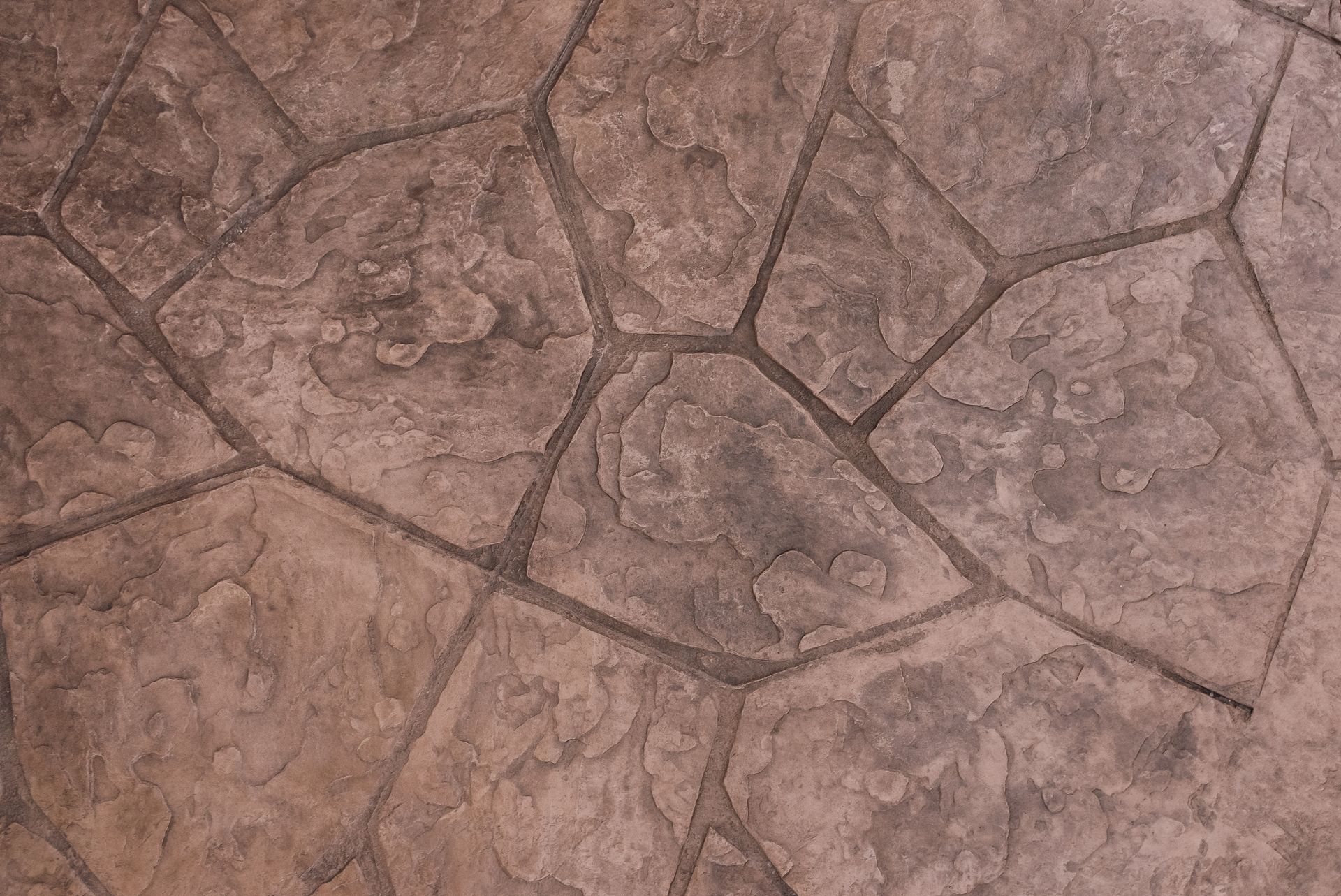 Brown and gray stamped concrete patio, with textured, irregular stone pattern.