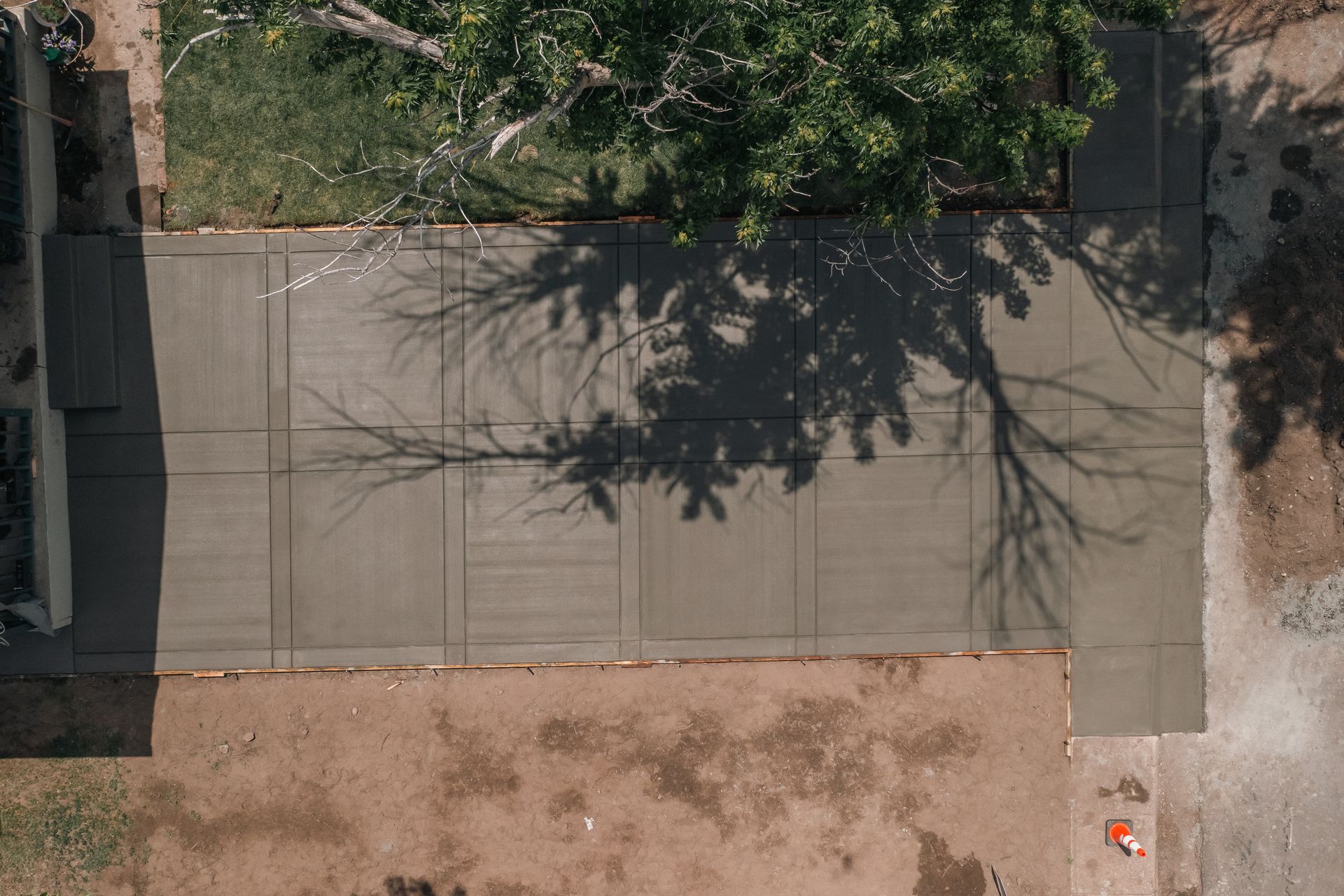 Overhead view of a newly poured concrete driveway, with tree shadows cast over it.