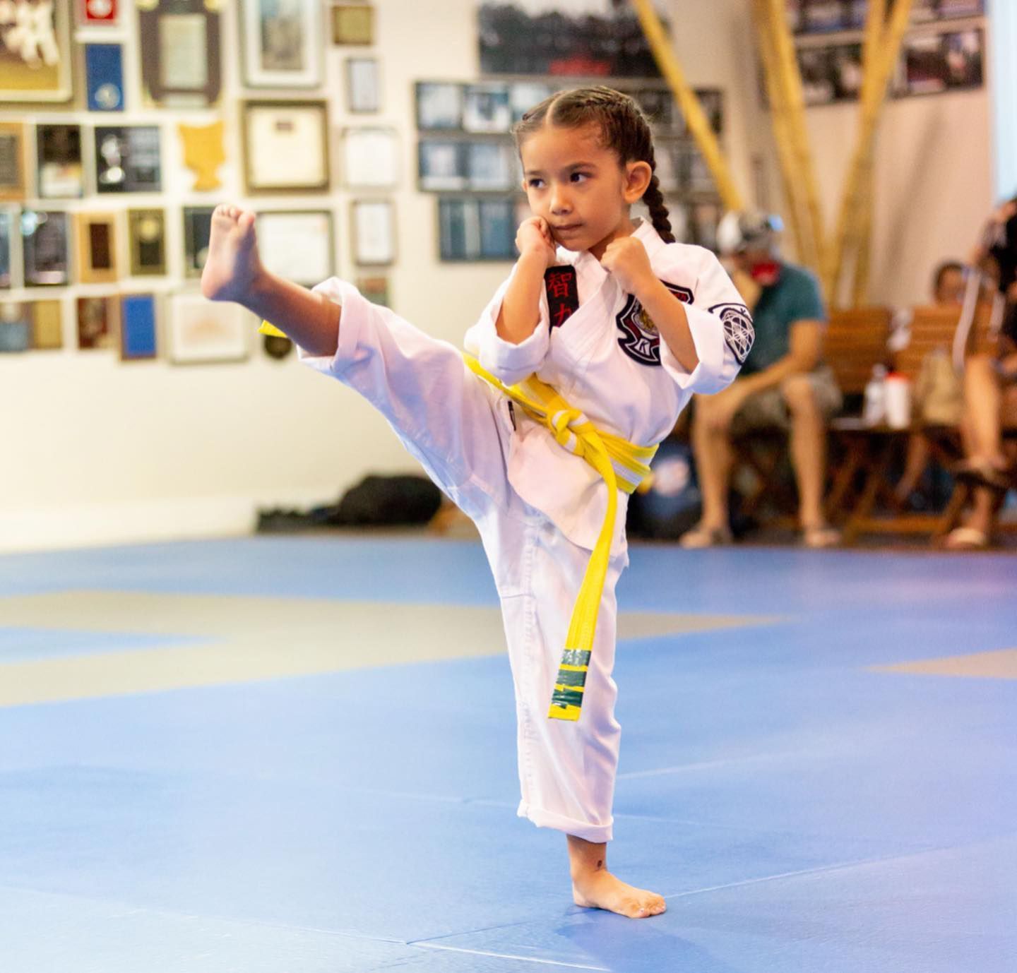 a young girl wearing a white karate uniform with a yellow belt