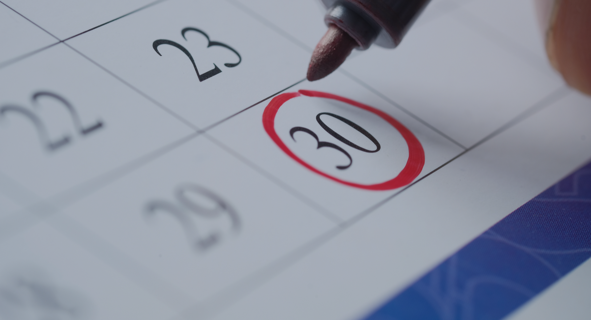 Hand circles the number 30 on a calendar with a red marker.