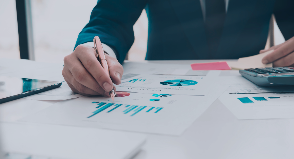 A man is writing on a piece of paper while using a calculator.