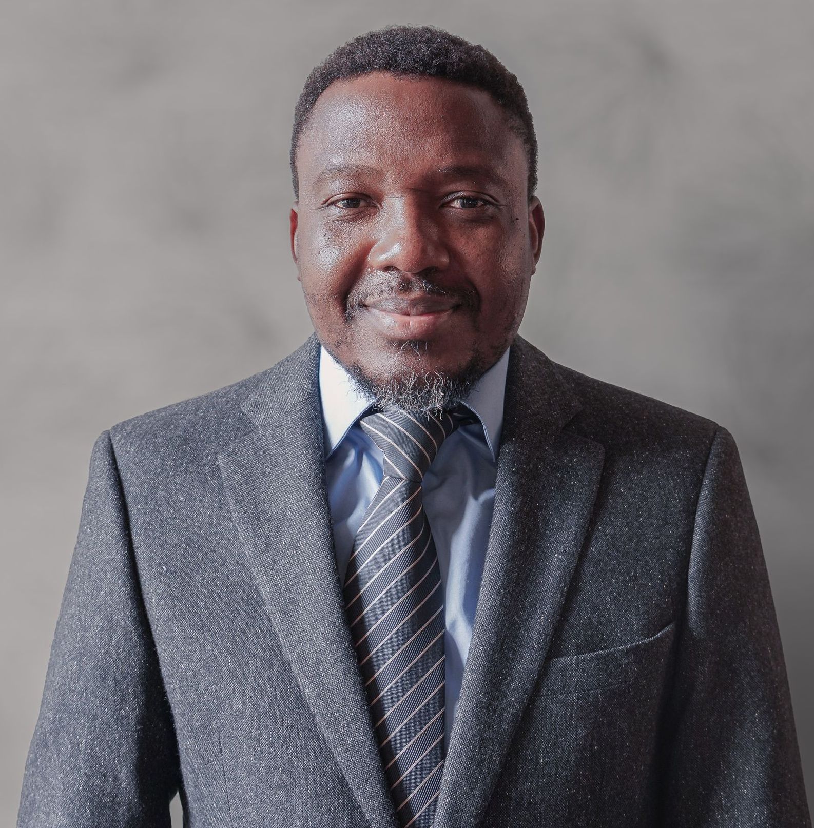 A man in a suit and tie is smiling for the camera
