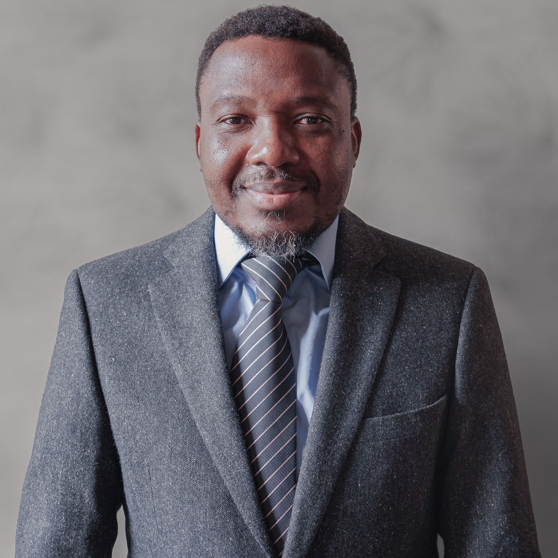 A man in a suit and tie is smiling for the camera