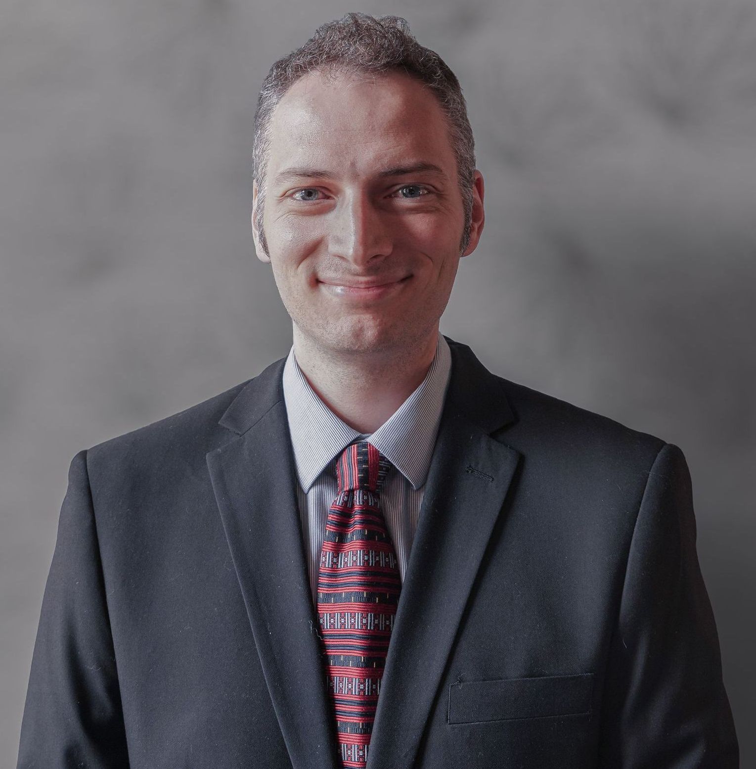 A man in a suit and tie is smiling for the camera