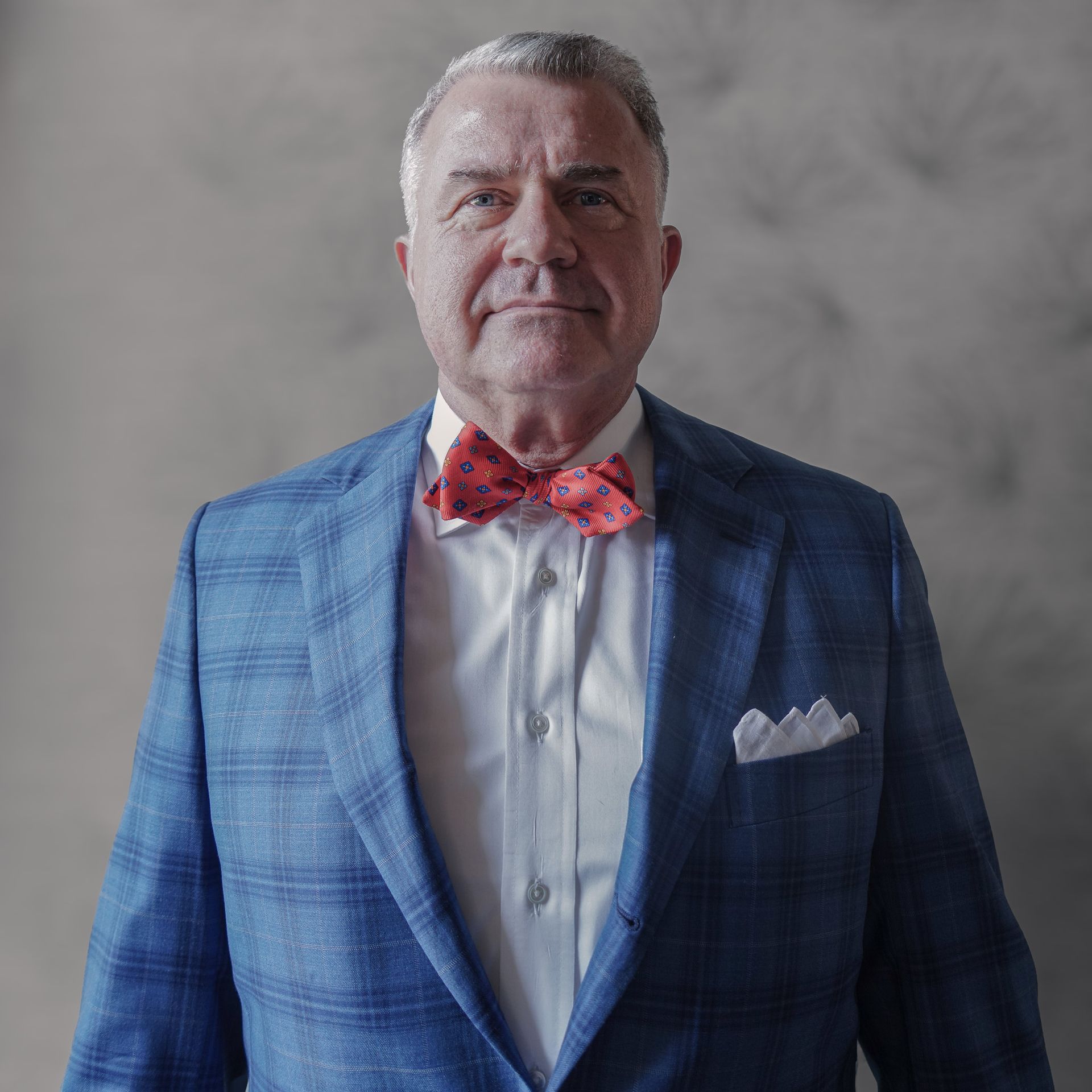 A man wearing a blue suit and a red bow tie