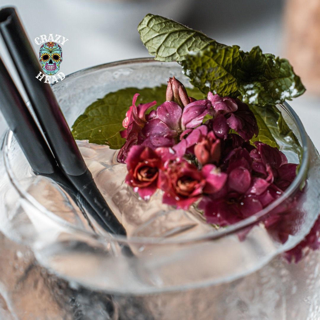 Un primo piano di un drink in un bicchiere con fiori e cannucce