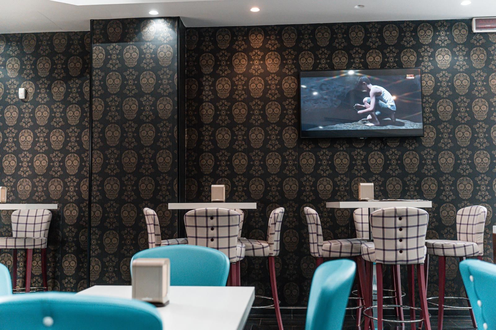 Una fila di tavoli e sedie di fronte a un muro con dei teschi sopra