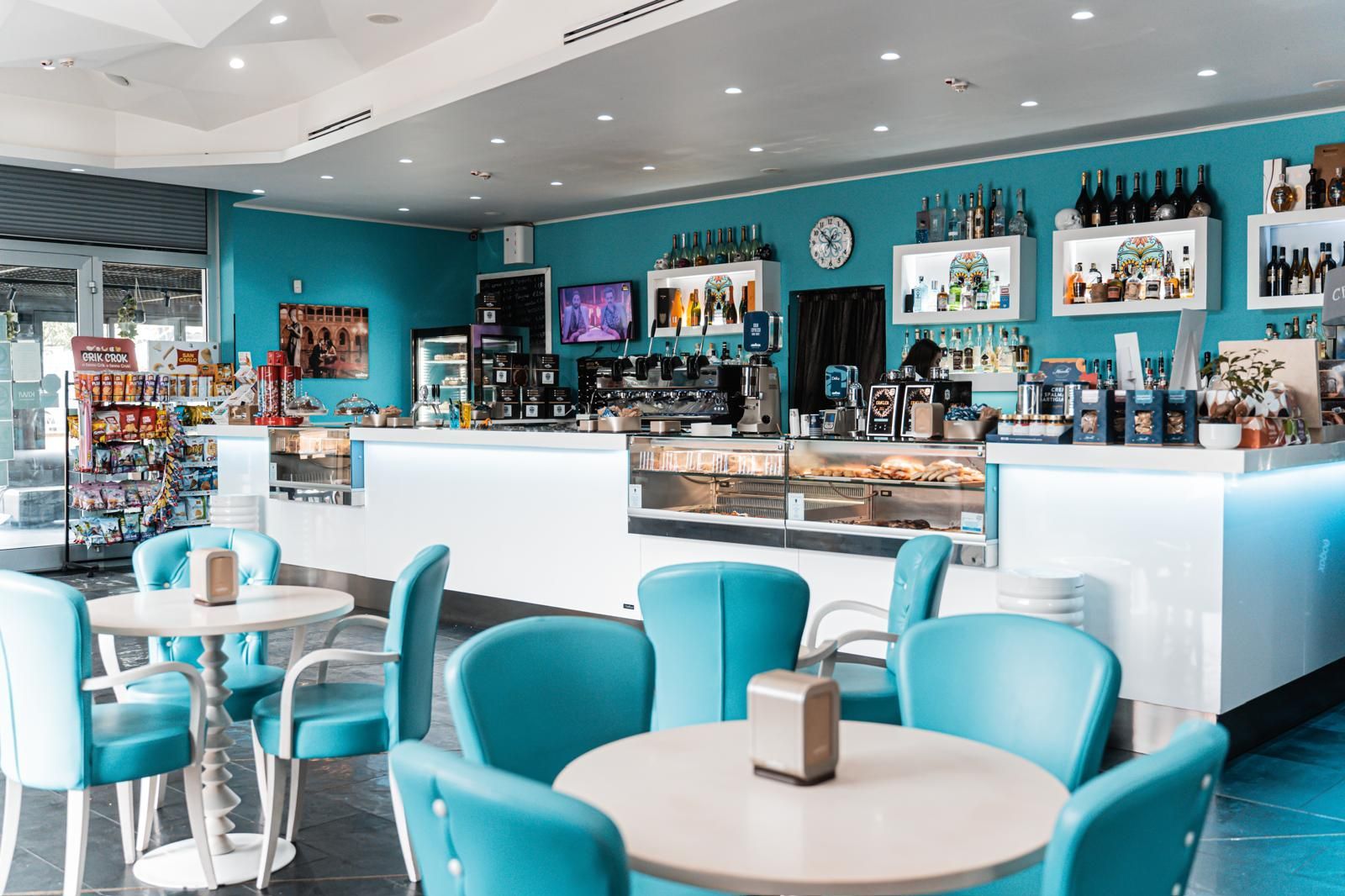 Un ristorante con sedie e tavoli blu e un bar.