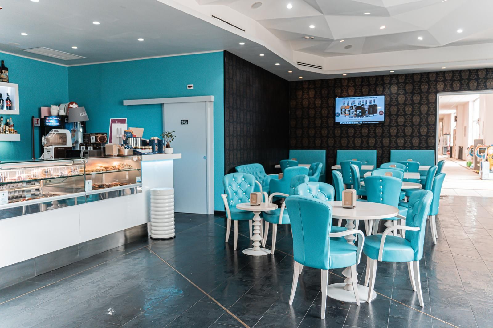 Un ristorante con sedie e tavoli blu e una televisione sul muro.