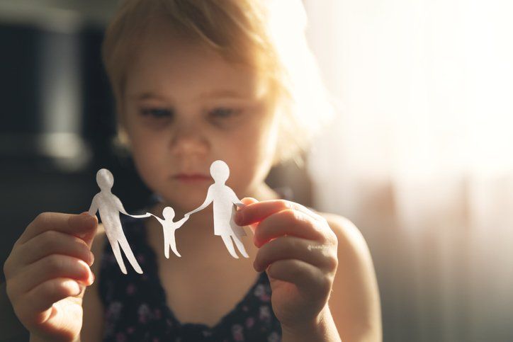 child holds fragile paper cutout of family holding hands