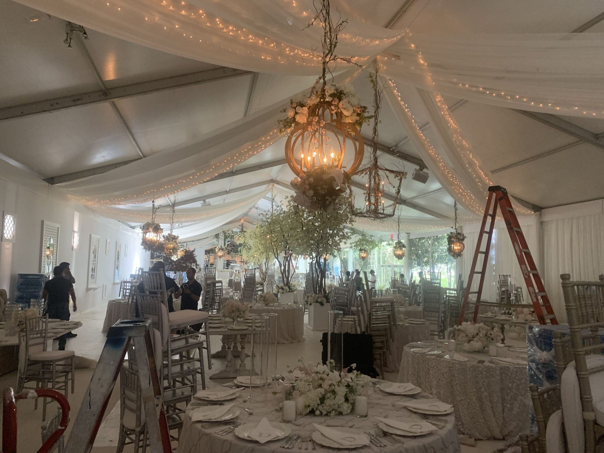 A large room with tables and chairs and a chandelier hanging from the ceiling.
