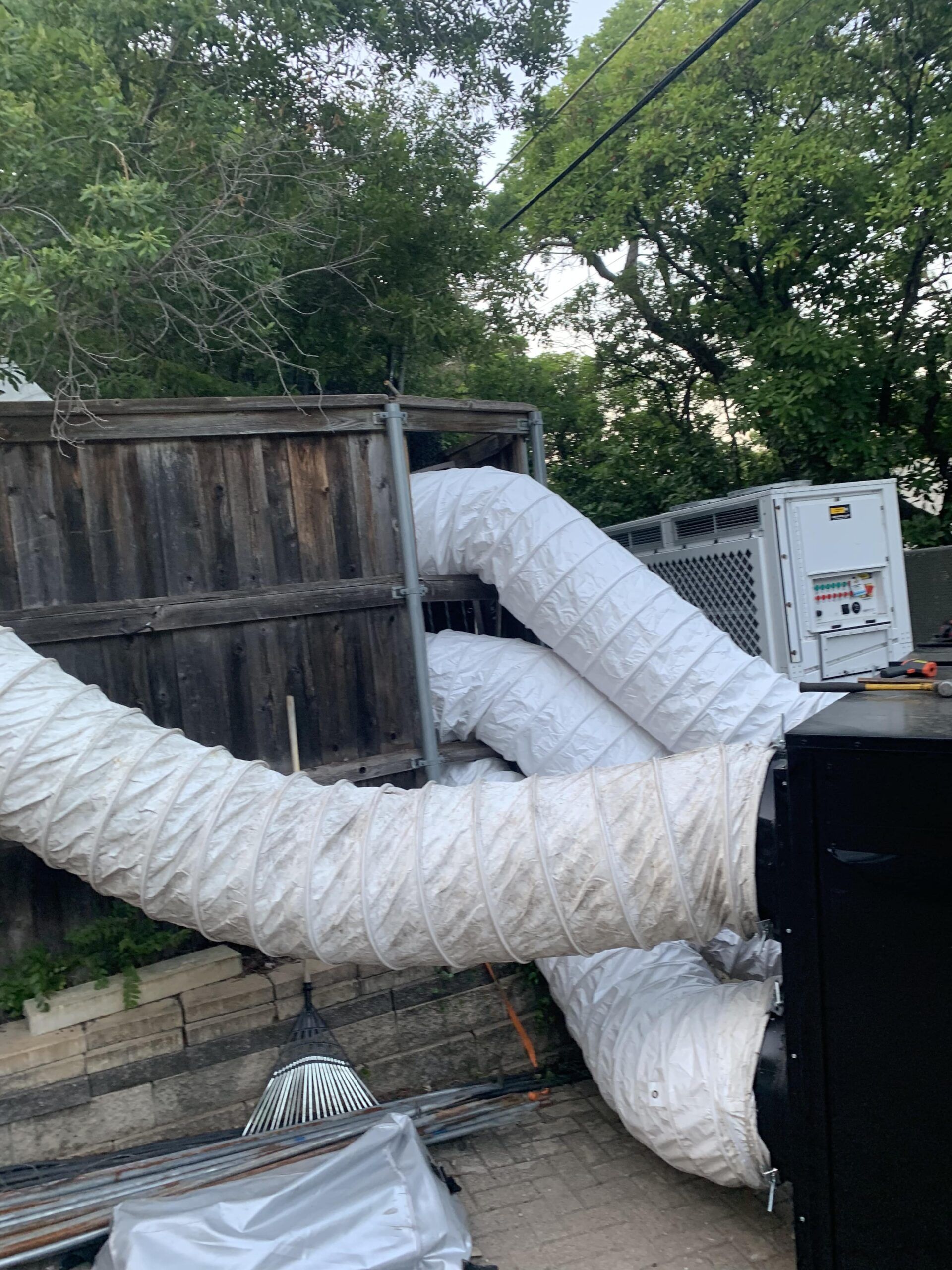 A bunch of white pipes are connected to a machine in a backyard.