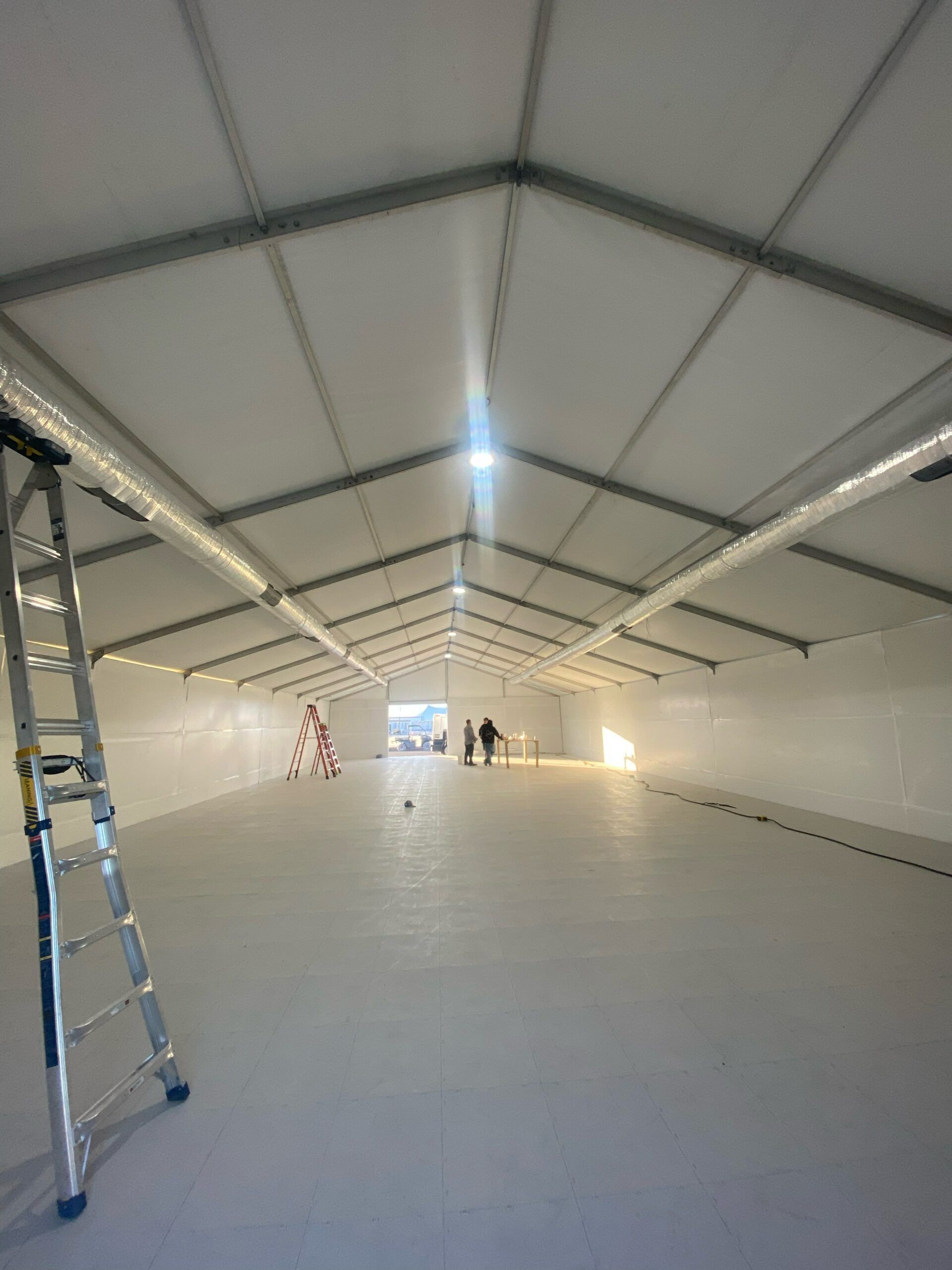 A large empty room with a ladder in the foreground