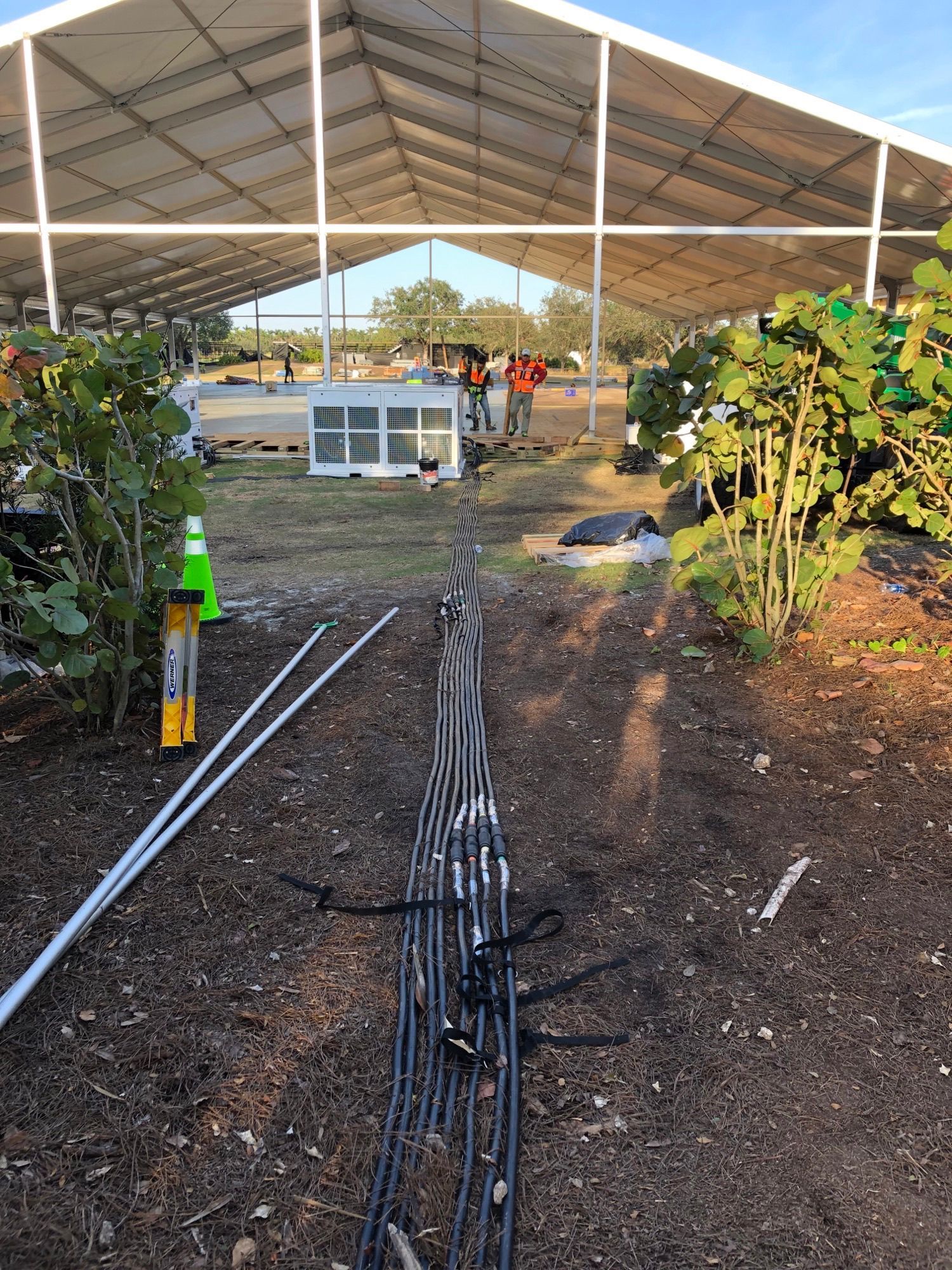 A large white tent is being built in the middle of a field.
