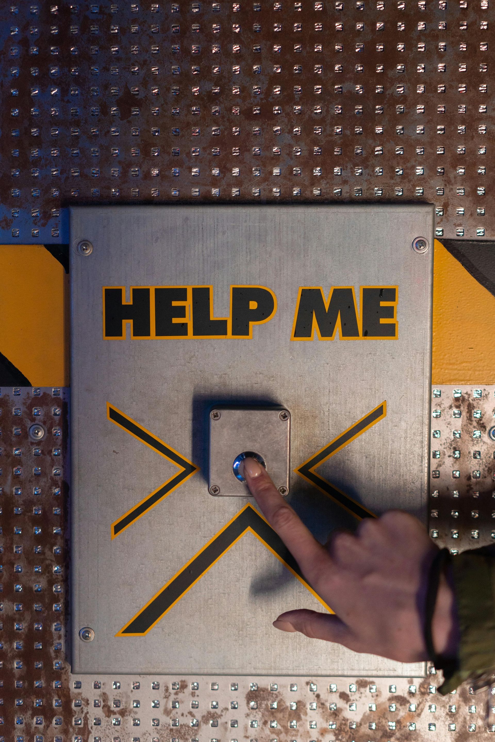 A person is pressing a button that says help me