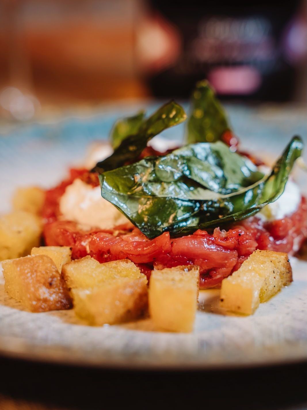 Pasta al sugo di pomodoro, foglie verdi croccanti e patate a cubetti su un piatto bianco.