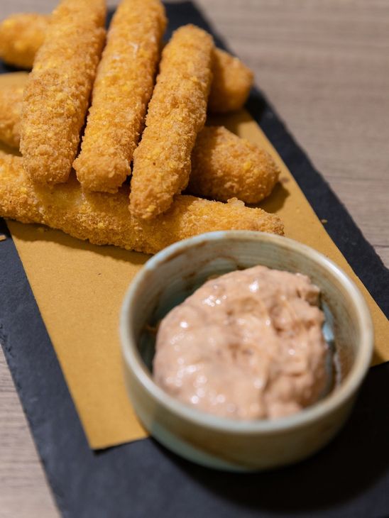 Bastoncini impanati con salsa d'accompagnamento, serviti su un piatto e un tovagliolo.