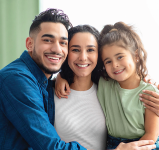 Three smiling people sitting close together on a couch, wearing blue, white, and green tops.