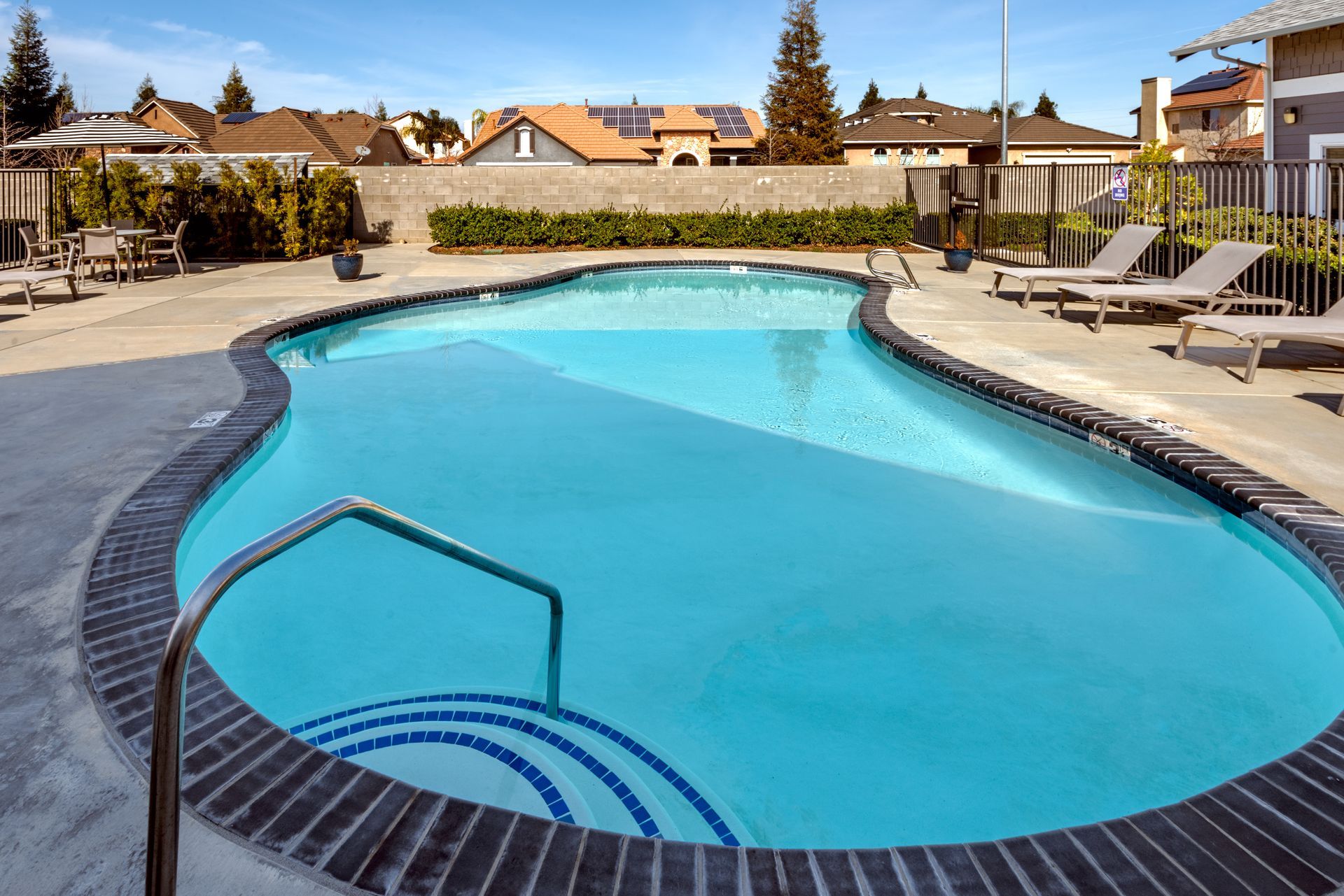 Outdoor swimming pool with clear blue water surrounded by brick.