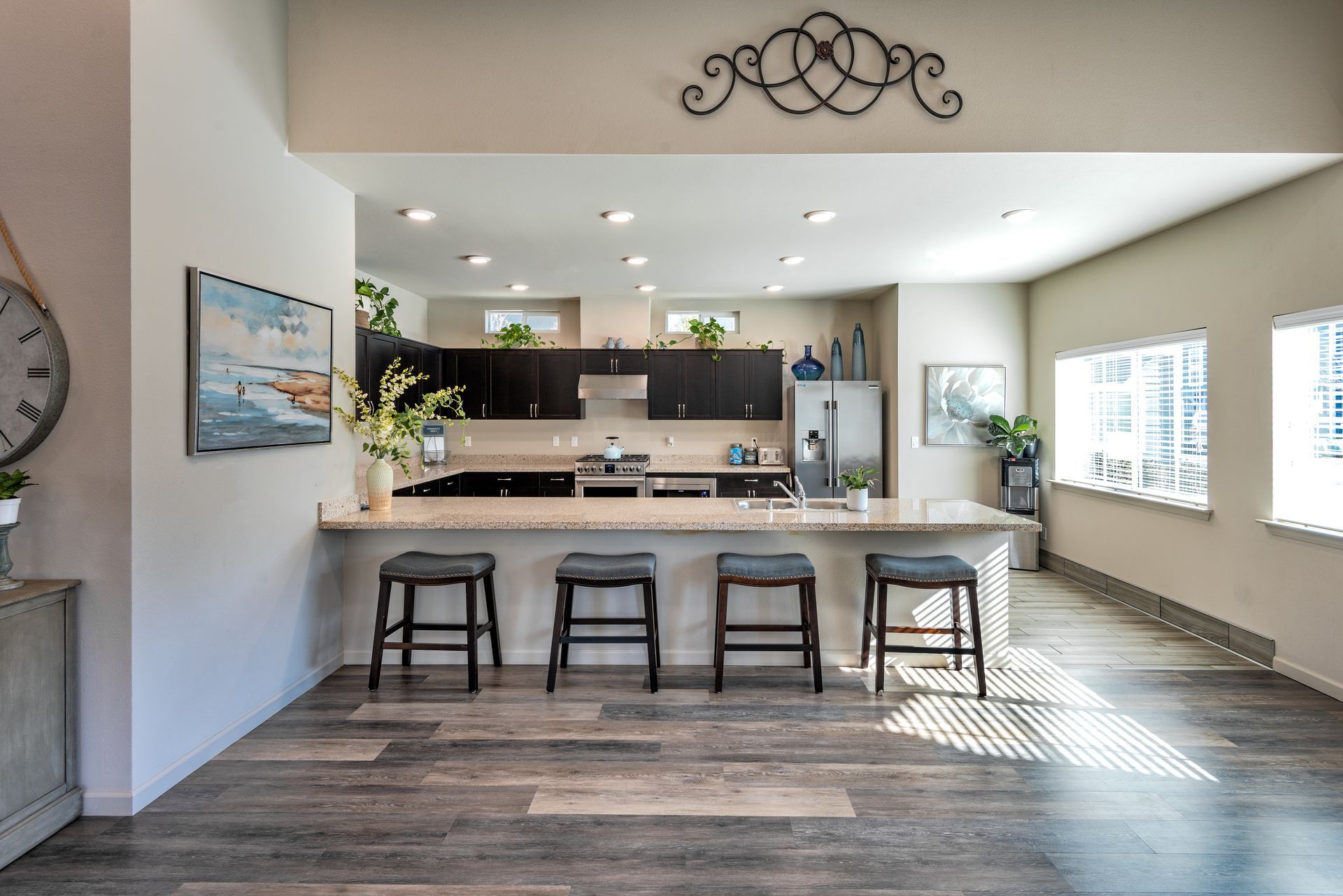 Modern kitchen with dark cabinets, island with stools, and hardwood floors.
