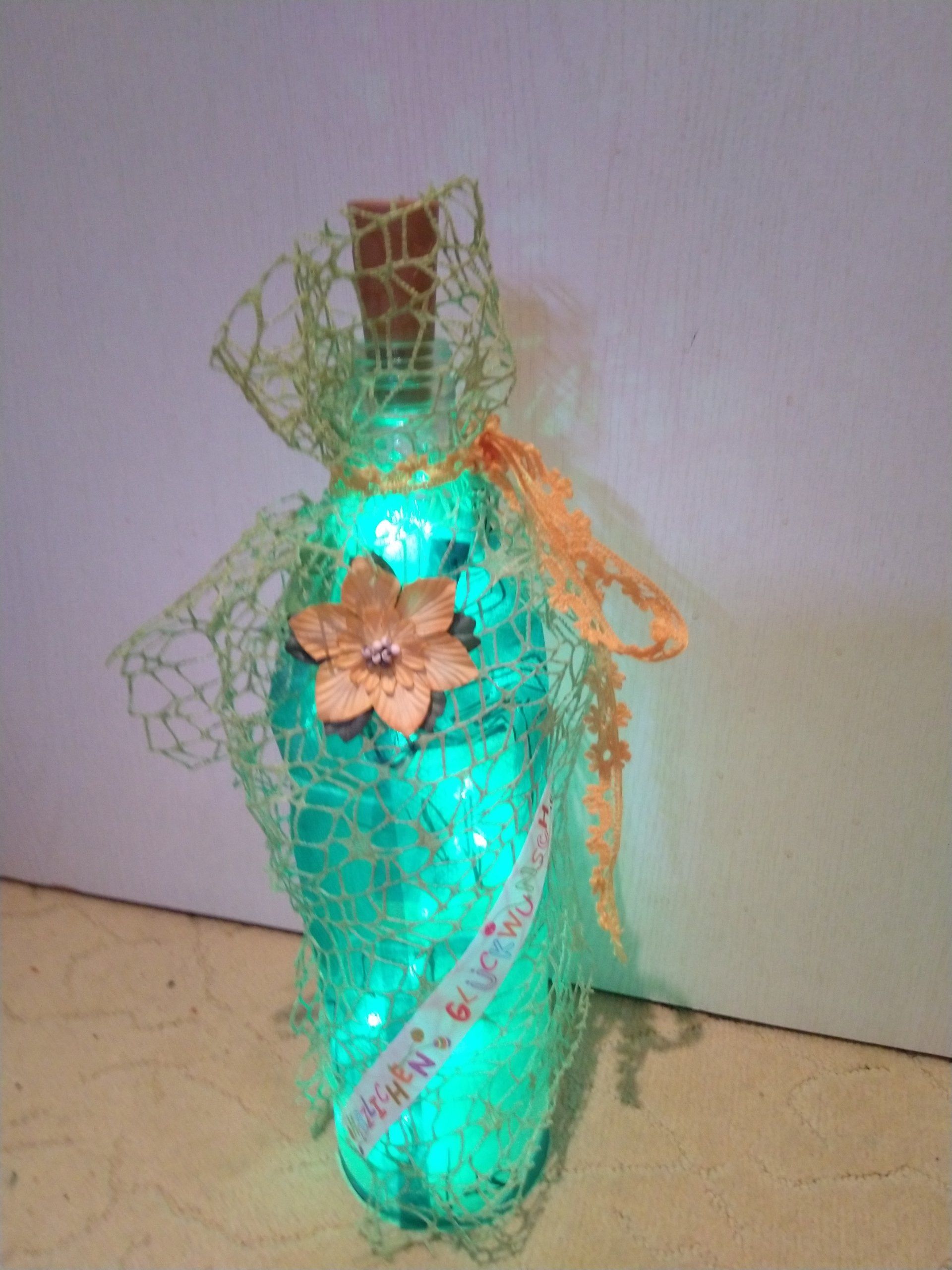 Eine beleuchtete Flasche mit einer Blume darauf