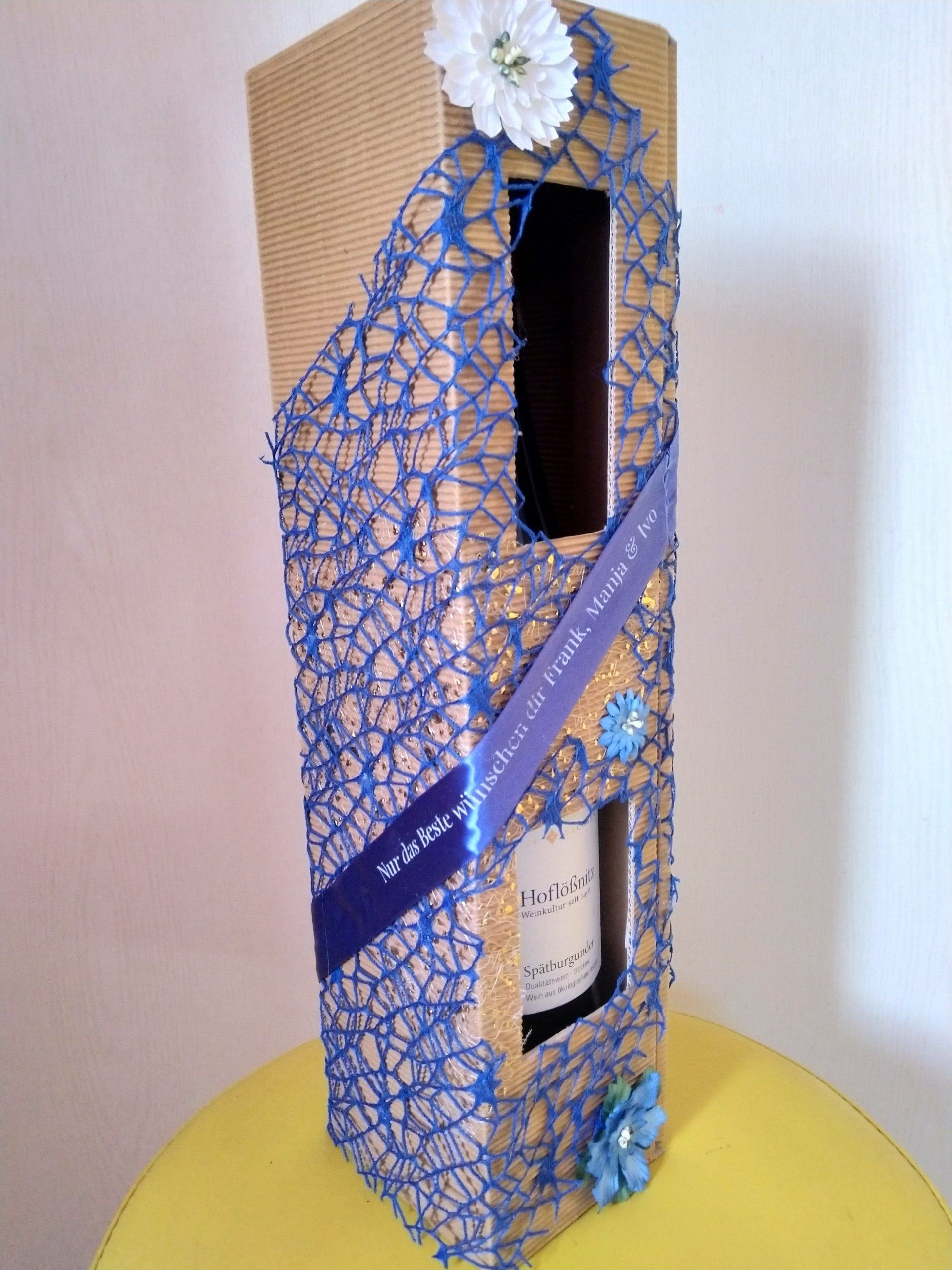 Eine Flasche Wein in einer Schachtel mit einer Blume darauf