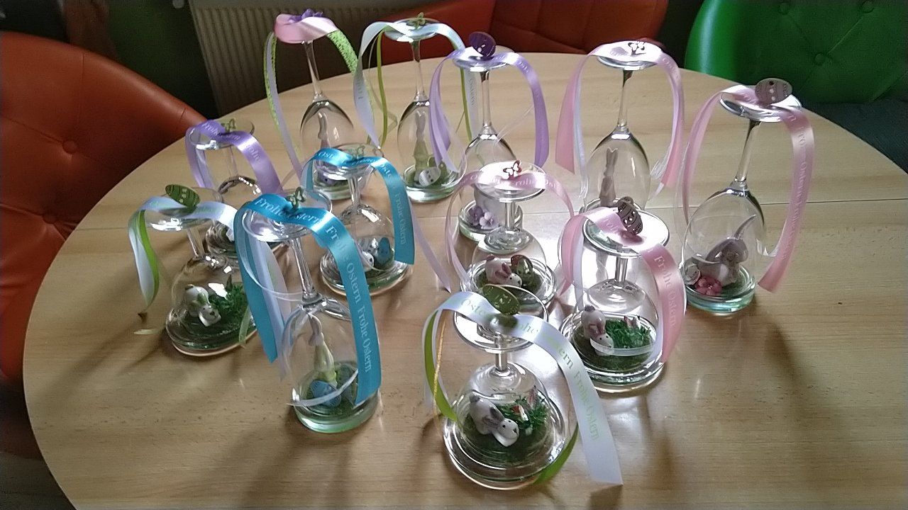 Ein Tisch mit Weingläsern, die mit Bändern und Blumen dekoriert sind.