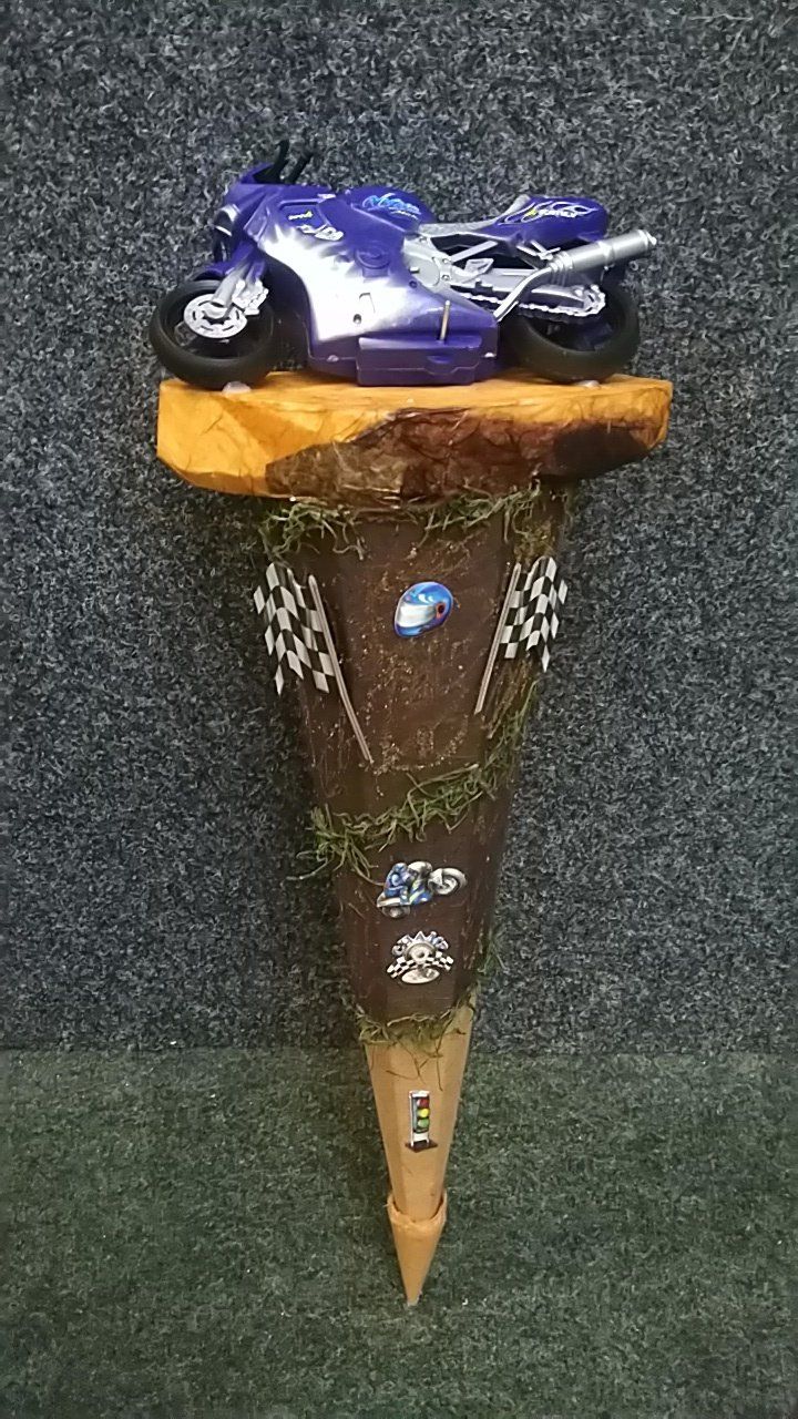 Auf einem Holzkegel sitzt ein Spielzeugmotorrad.