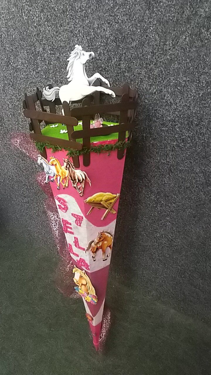 Ein rosa Kegel mit Pferden und einem Zaun darauf.