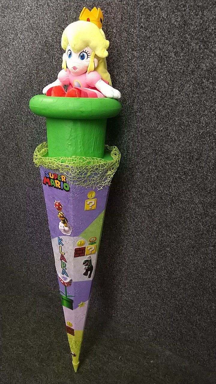 Eine Prinzessin-Peach-Puppe sitzt auf einem lila-grünen Kegel.