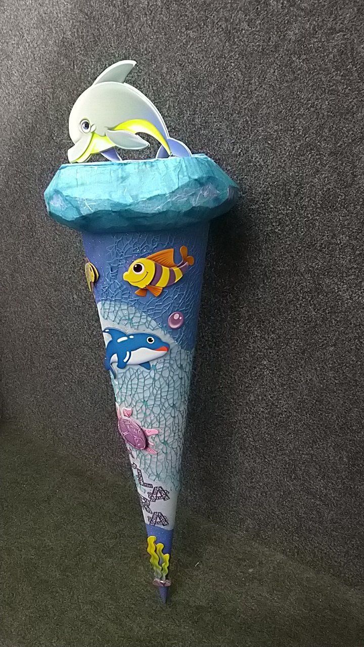 An einer Wand hängt ein Kegel mit einem Delphin und einem Fisch darauf.