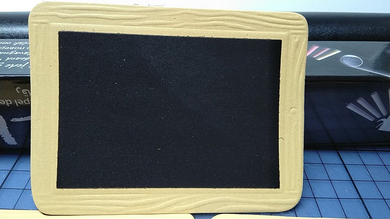 Eine kleine Tafel mit einem Holzrahmen steht auf einem Tisch