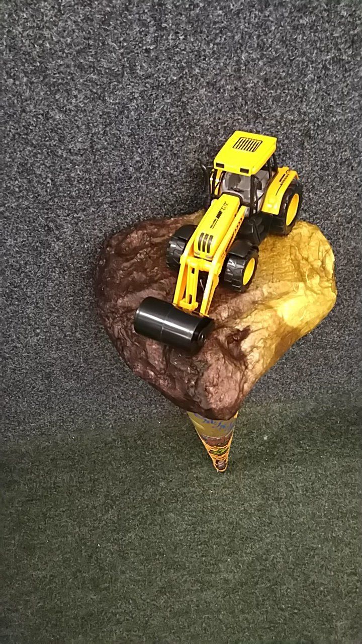 Auf einem Felsen steht ein Spielzeugtraktor.