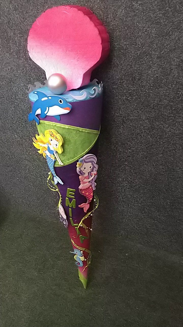 Eine bunte Eistüte mit Meerjungfrauen und Delfinen darauf.