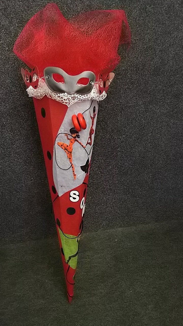 Auf einem Tisch steht ein roter Kegel mit einem Marienkäfer darauf.