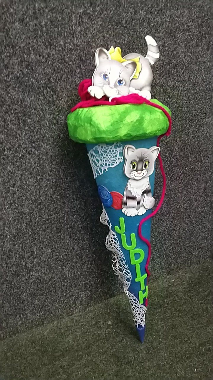 Ein blau-grüner Kegel mit zwei Kätzchen darauf.